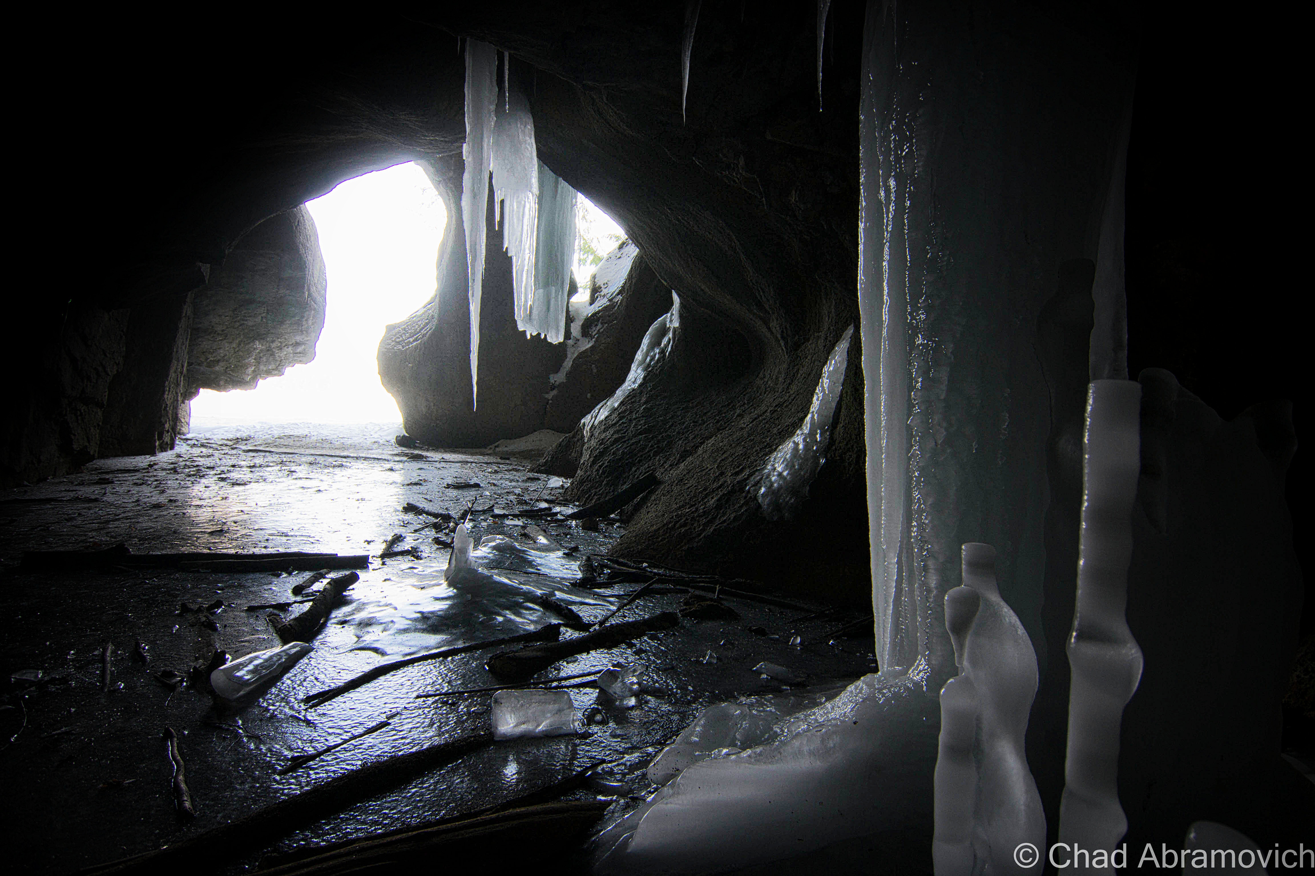 As the cave ascended further back into the hill, I noticed there was movement beneath the layers of ice under my feet. There was running water lapping below in black pools, and the darting motions of hundreds of minnows 