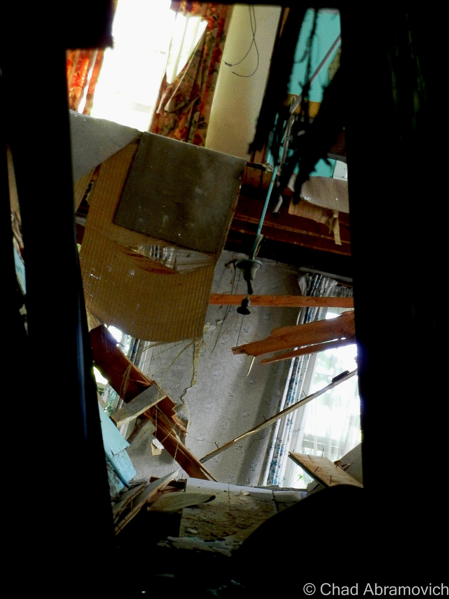 This has to be one of my favorite pictures I’ve taken. In 2011, a massive crack was heard bellowing through the Sudbury woods, followed by a hideous collapse that startled wildlife and neighboring residences. When the dust settled, the pieces of the puzzle were revealed. Part of Hyde Manor’s second floor had finally given way, due to years of water damage and rot. When that gave, the upper floors tumbled down with it, creating a huge hole in the front of the building – a landscape of vibrant exposed wallpapers and hanging doors. This picture was taken from the first floor, through the chunk of a former doorway of a guest room that had settled near the staircase. Through the door, it gives you a bizarre perspective of the 2nd and 3rd floors, and the individual guest rooms (or what’s left of them)